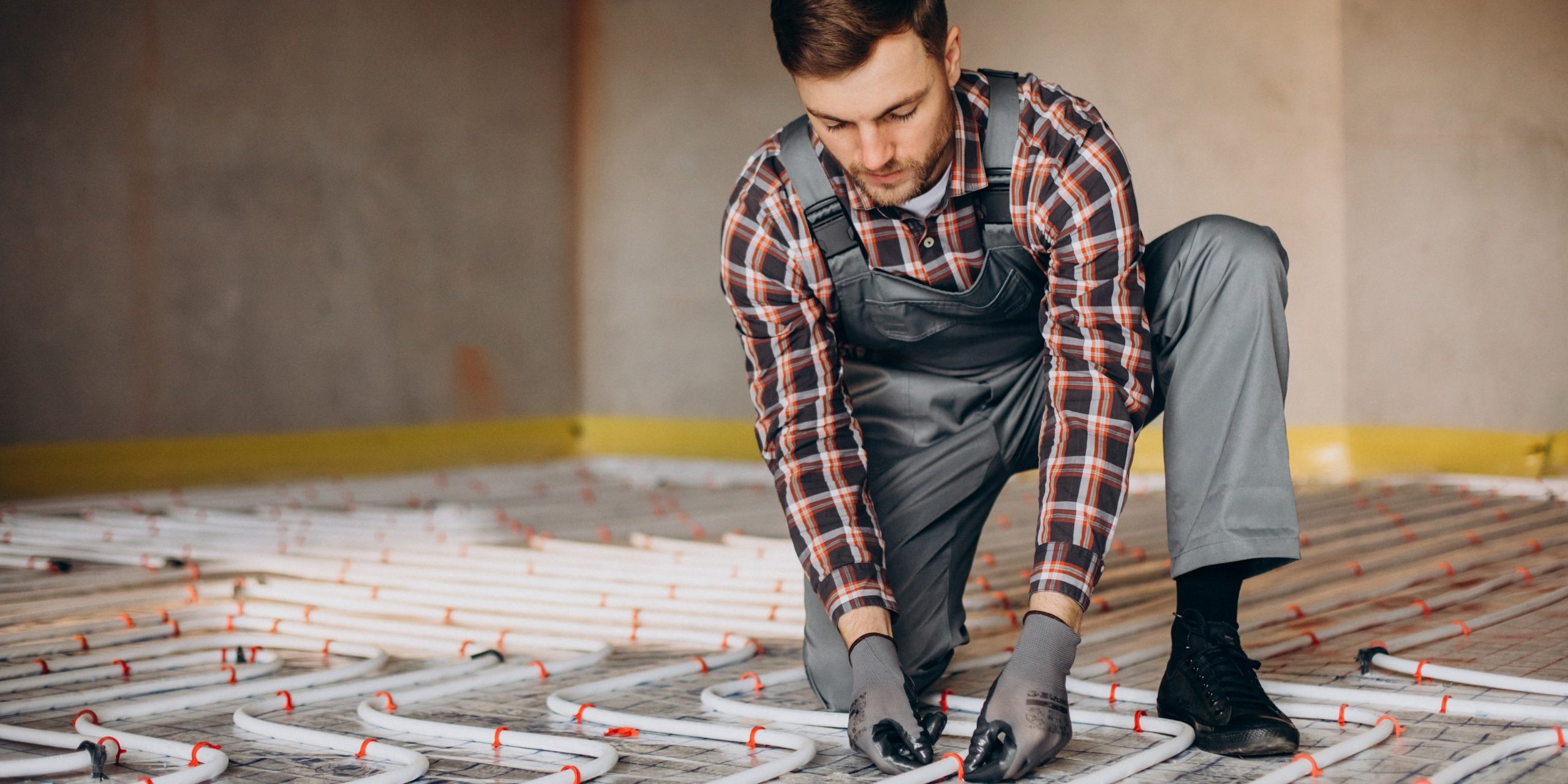 Service man instelling house heating system under the floor