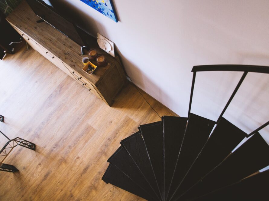 Vista desde arriba desde unas escaleras de caracol donde se ve un salón con suelo de parquet