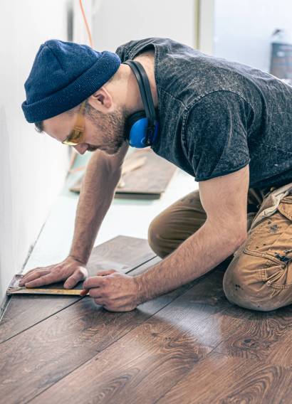 Trabajador midiendo un tablón de tarima laminada en el suelo